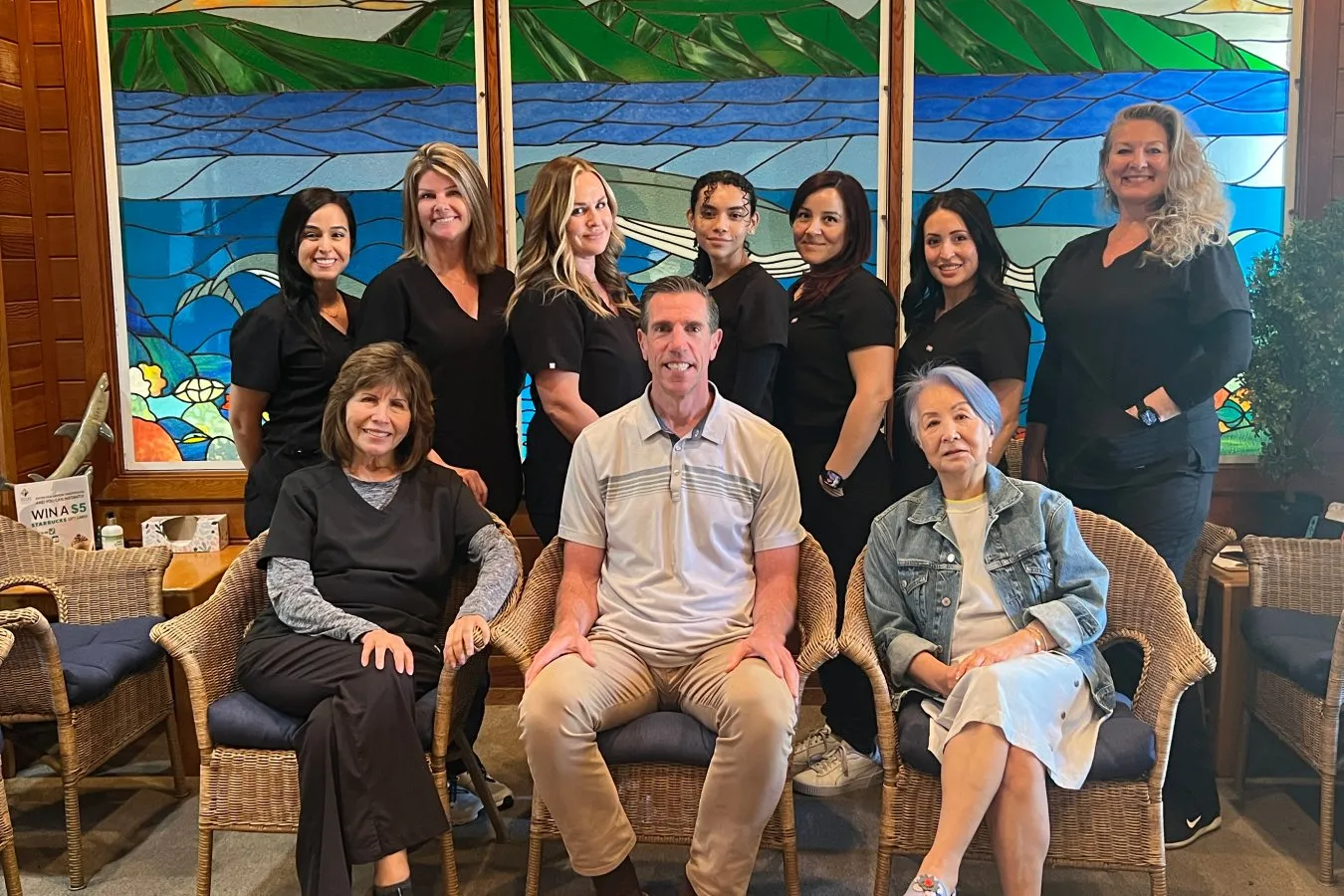 Team of orthodontic professionals at Potter Orthodontics in Yorba Linda, CA, featuring Dr. Jeffrey Potter, DDS, MS, and staff in black uniforms, set against a colorful stained glass backdrop.