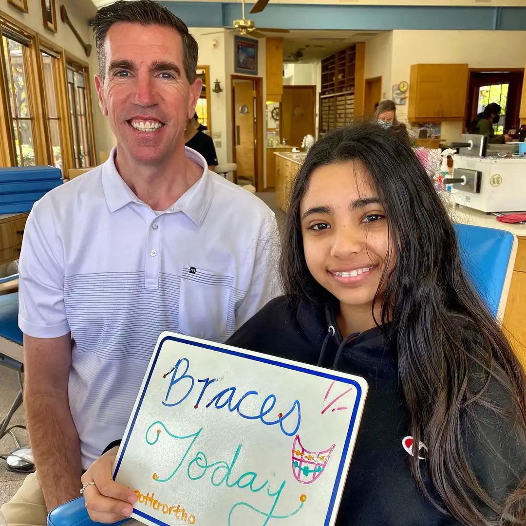 Dr. Potter smiling with patient holding sign that says, "Braces Today!"