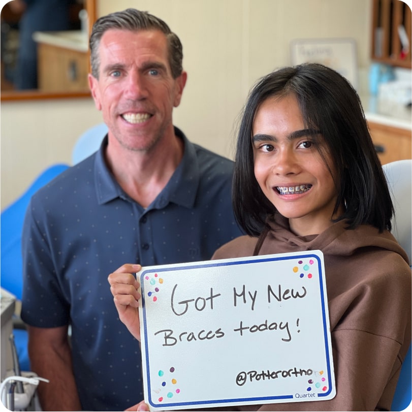 Dr. Potter and young girl with new braces holding sign