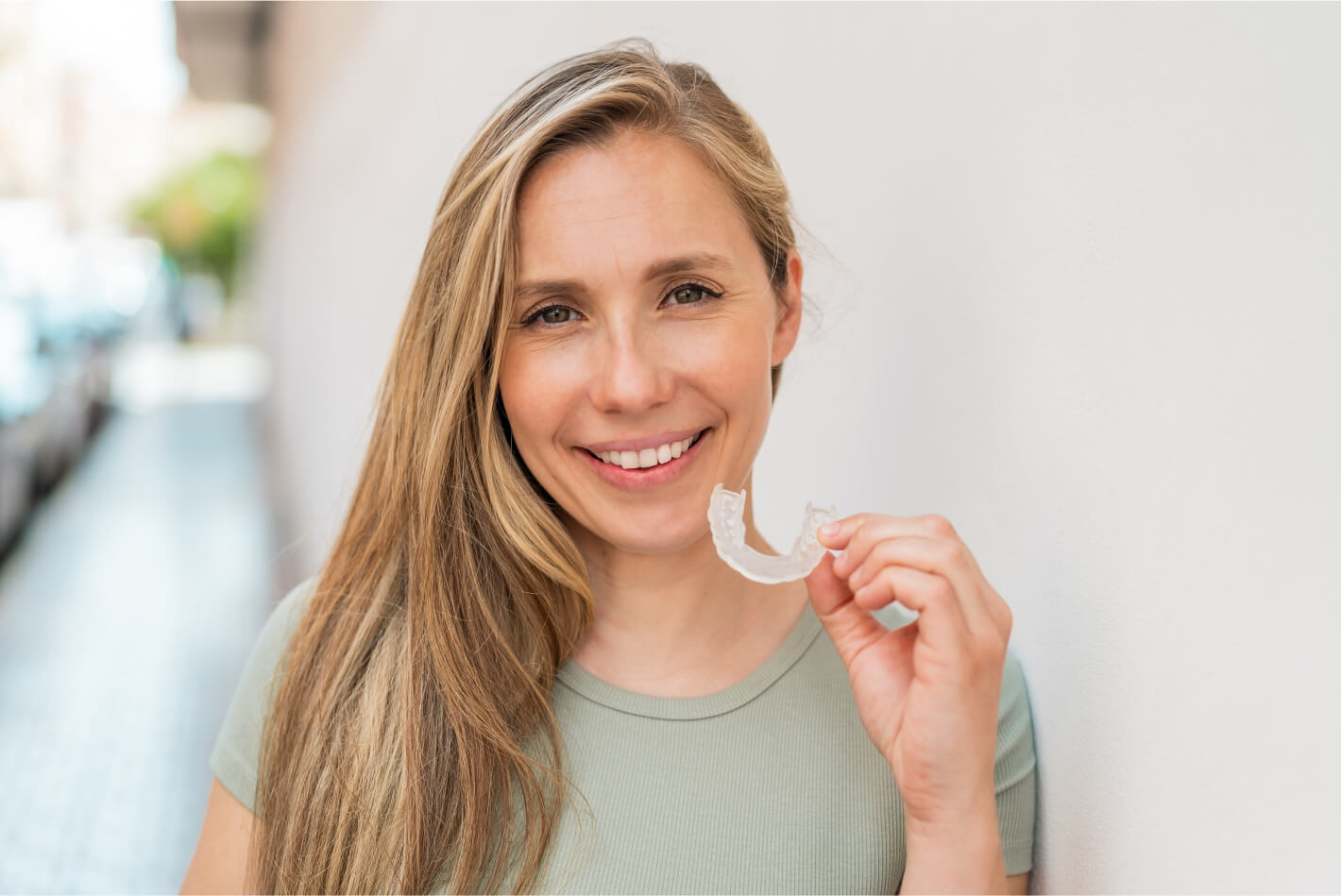 Woman smiling holding clear aligners