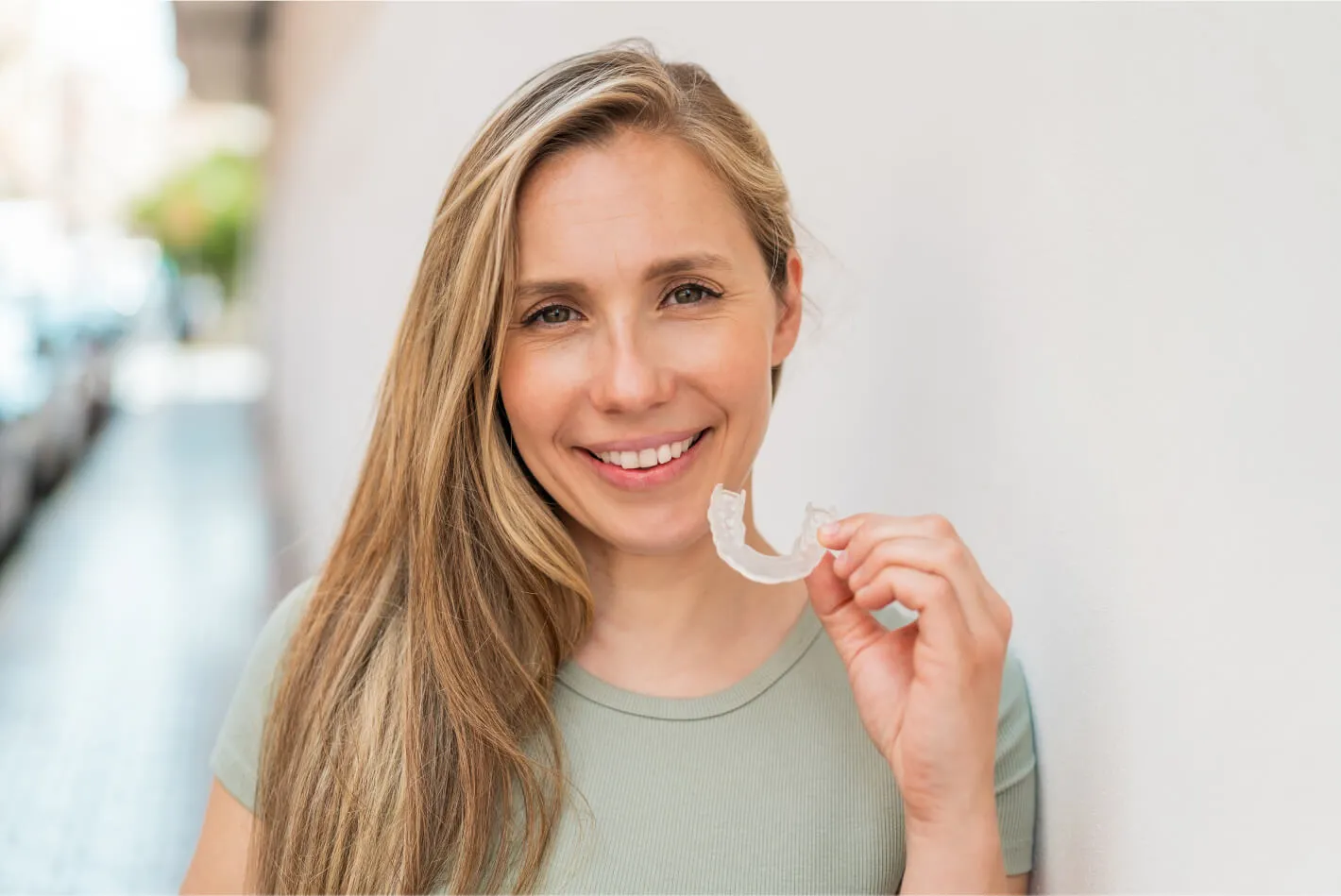 Woman smiling holding clear aligners