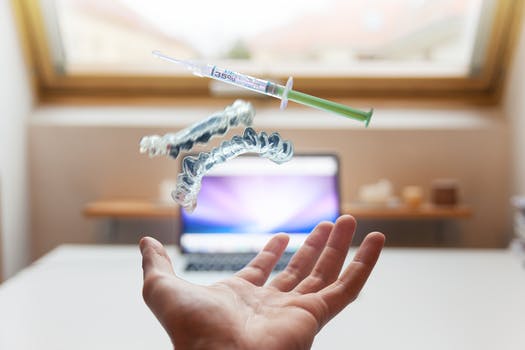 Hand with Invisalign aligners and needle hovering above it
