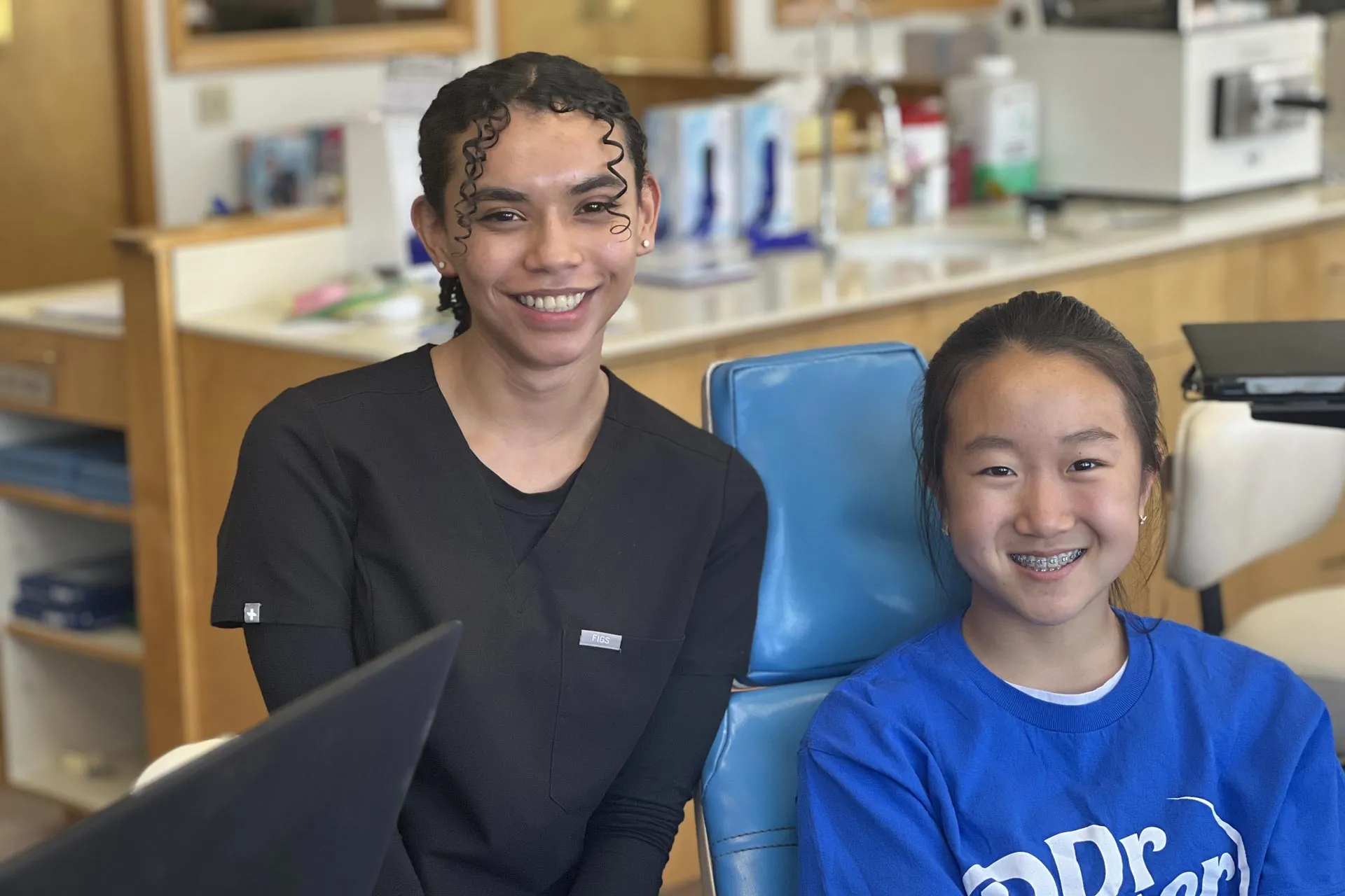 Orthodontic patient and dental professional smiling together in an orthodontic office, showcasing a friendly environment for children receiving braces treatment.